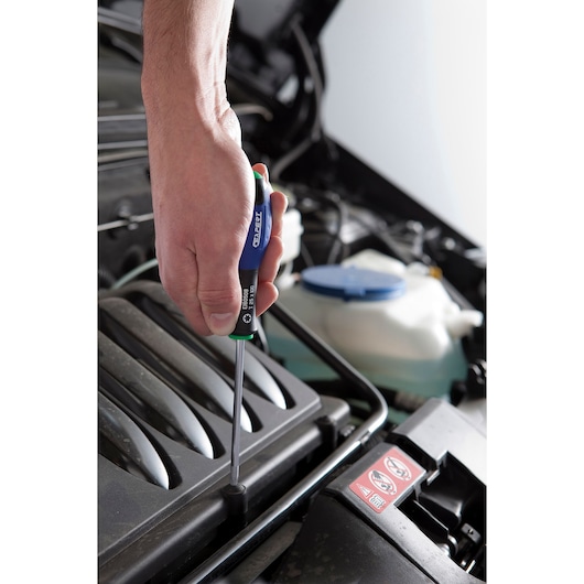 Facom E160505 screwdriver used to tighten a screw on a car engine cover with a close-up view of the hand.