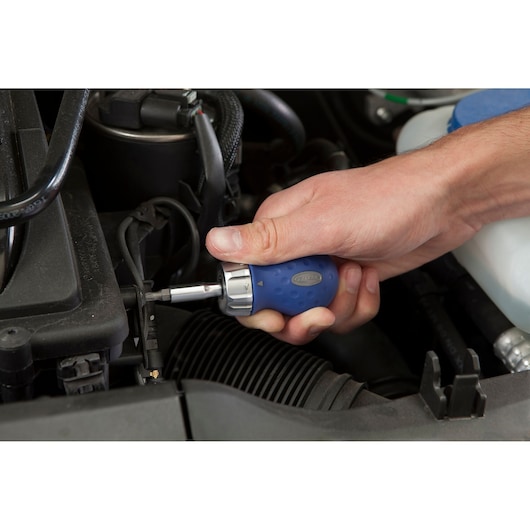 Facom E160803 blue ergonomic screwdriver used for automotive maintenance, close-up in engine bay.