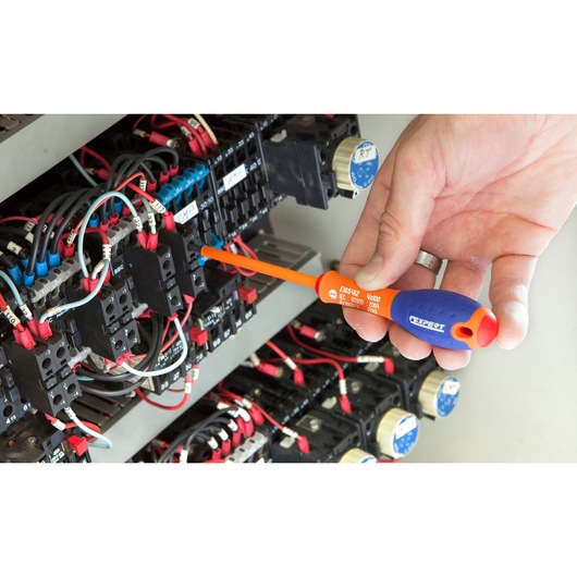 Facom E165412 insulated screwdriver used on electrical panel, orange and blue handle, close-up.