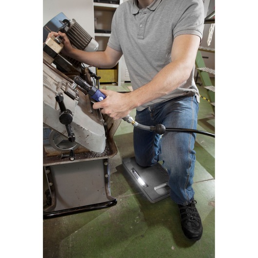 Facom E200131 kneeling pad used by worker in workshop, providing comfort on green floor.
