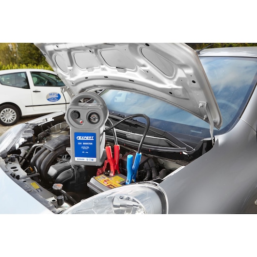 Facom 12V booster E200408 connected to car battery under open hood, jump-starting vehicle.