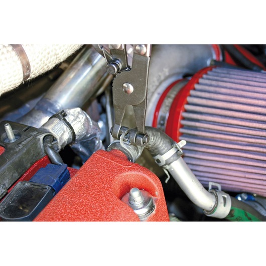 Facom E200507 pliers used on hose clamp in automotive engine close-up photography.
