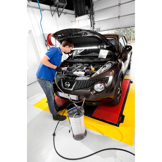 Facom E200512 automotive fluid extractor in use, with operator servicing car engine in workshop.