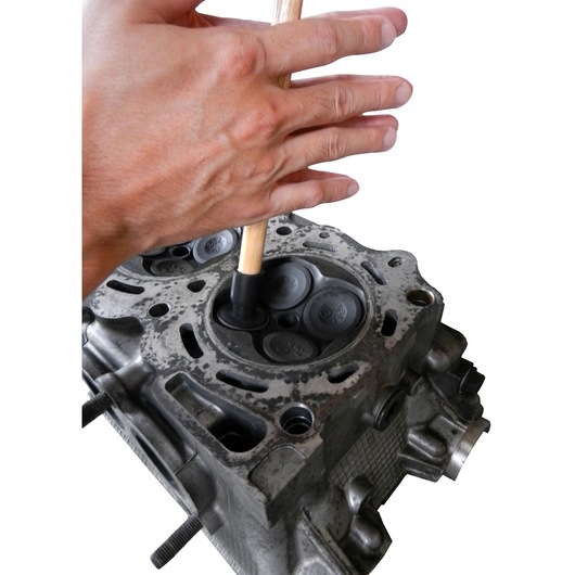 Facom E200518 valve lapping tool in use on engine cylinder head, close-up with hand, white background.