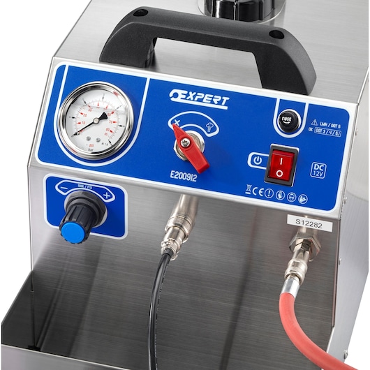 Close-up view of a Facom E200912 Expert device. The device features a blue control panel with a pressure gauge, on/off switch, rotary knob, and connection ports for cables. The handle is mounted at the top, and the device is made of metallic material.