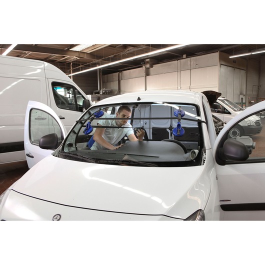 Facom E201501 automotive glass suction cup tool in use on car windshield, photographed in workshop setting.