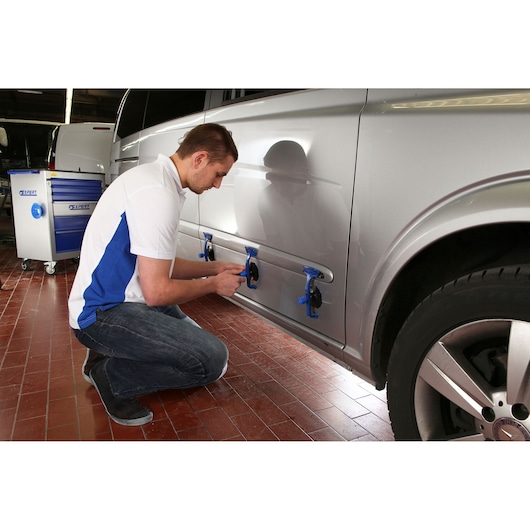 Facom E201507 photography of technician using car dent repair tools on silver vehicle side.
