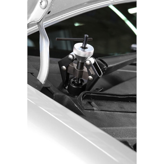 Facom E201512 wiper arm puller tool in use on a car windshield, close-up photography.