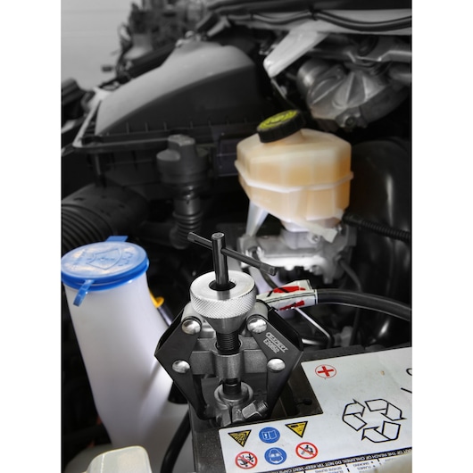 Facom E201512 automotive puller tool in use on a car engine, close-up angle.