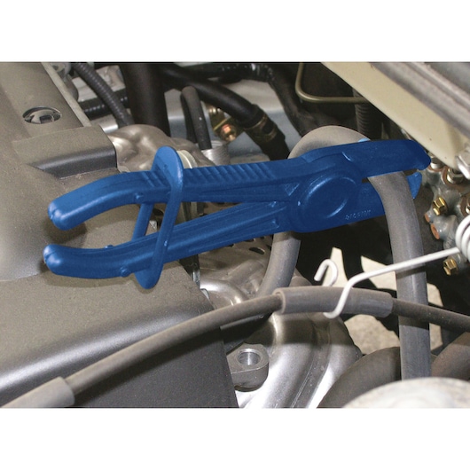 Facom E201701 blue hose clamp pliers in use on an engine hose during automotive maintenance.