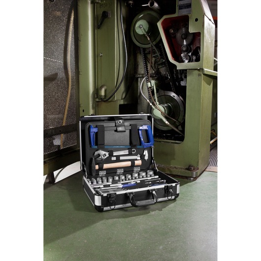 Facom E220109 tool kit with assorted hand tools in open case near industrial machine.