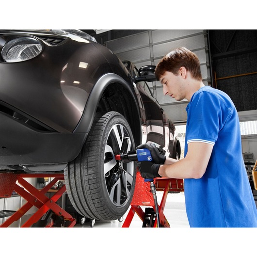 Facom E230110 impact wrench used by technician on car wheel in workshop.