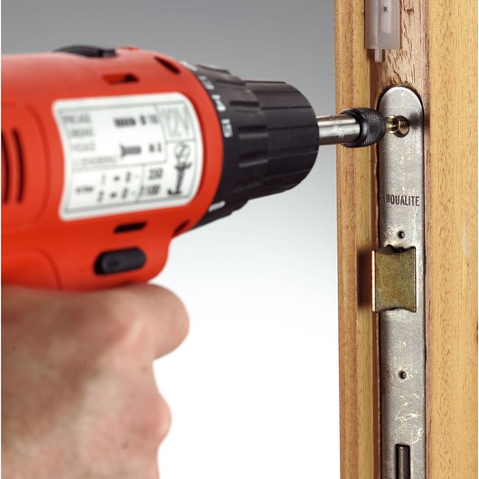 Facom ED_132T power drill driving screw into door lock plate, close-up photography.