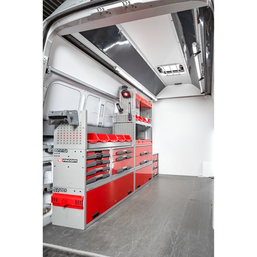 Interior view of a van equipped with red and grey Facom storage units, drawers and shelves, designed for organizing tools and equipment.