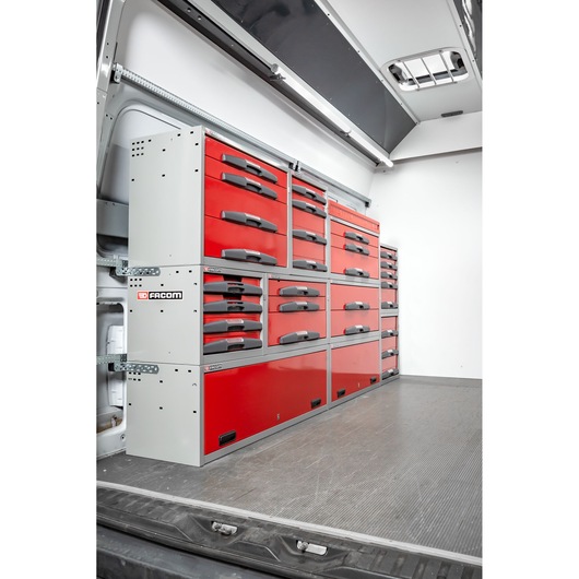A modular storage system with multiple red and grey drawers by Facom, installed along the side of a vehicle interior.