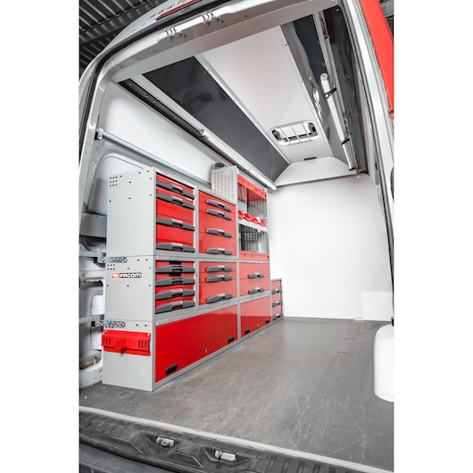 Interior view of a van equipped with Facom branded red and gray storage drawers and cabinets, organized along the left side for tool and equipment storage.