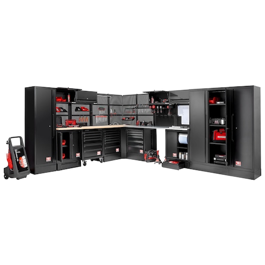 Large modular black workshop storage system from Facom, featuring multiple cabinets, tool drawers, wall-mounted racks, and a workbench, fully equipped with various tools and equipment.