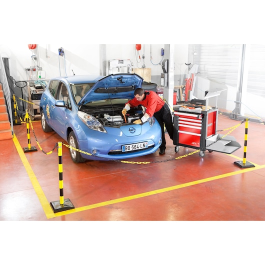 Facom J121AVSE tool trolley near technician working on car engine in workshop.