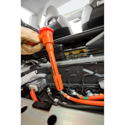 Photo of Facom J210AVSE insulated tool in use on high-voltage cables inside a car, close-up view.