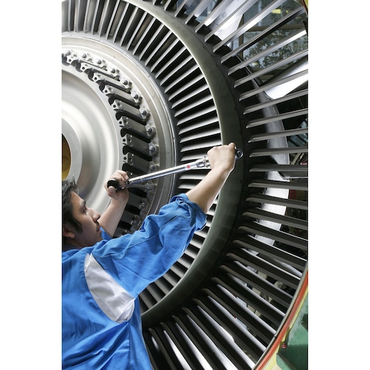 Facom J306A100 torque wrench used by technician on large turbine, side angle, industrial setting.