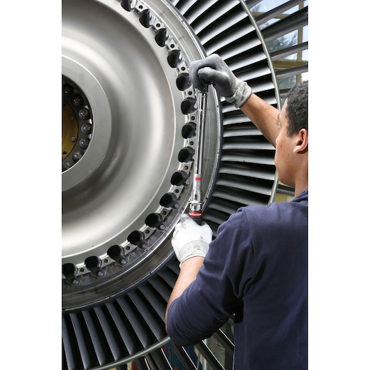 Facom J306A50 torque wrench used by technician on large industrial turbine, close-up action shot.