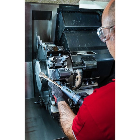 Photo of person using Facom J.307-50D digital torque wrench on industrial machinery.
