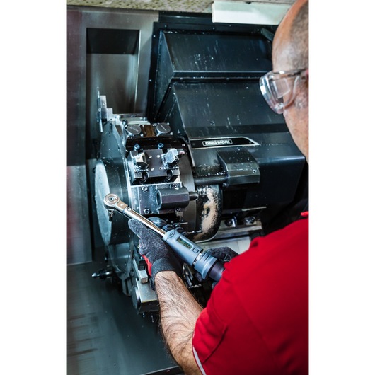 Photo of person using Facom J.307A50 digital torque wrench on industrial machinery.