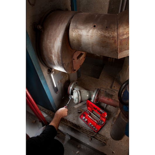 Facom red tool kit JXL_171 with sockets in use near industrial pipe, photography indoors.