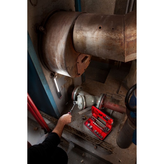 Facom red toolkit JXL_DBOX1 in use on industrial piping, visible sockets and ratchet in photography.
