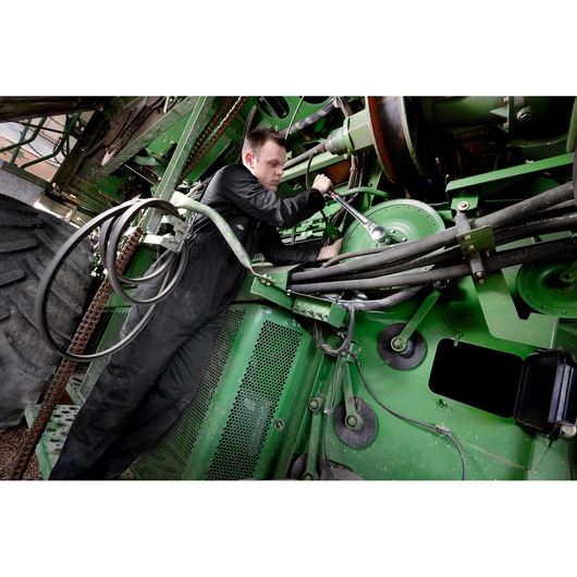Facom KL_161 photography of mechanic using tool on green agricultural machinery.