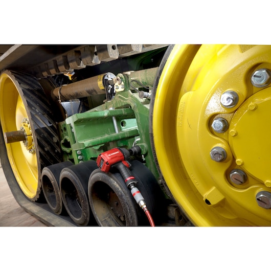 Facom NK.3000FPB red impact wrench connected to large yellow and black tracked machinery wheel.