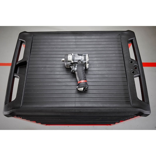 Facom NS2500G compact impact wrench with black and red grip on top of a black tool chest, top view.