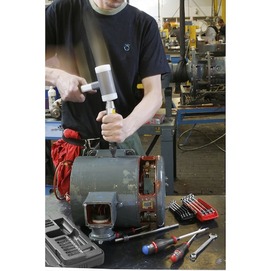 Facom NS260A photography of mechanic using mallet and tools on industrial motor in workshop setting.
