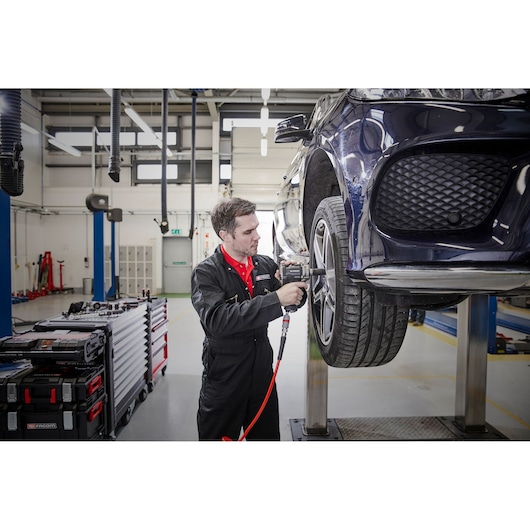 Facom NS.3100GPB photography of mechanic using tools on car wheel in garage workshop.