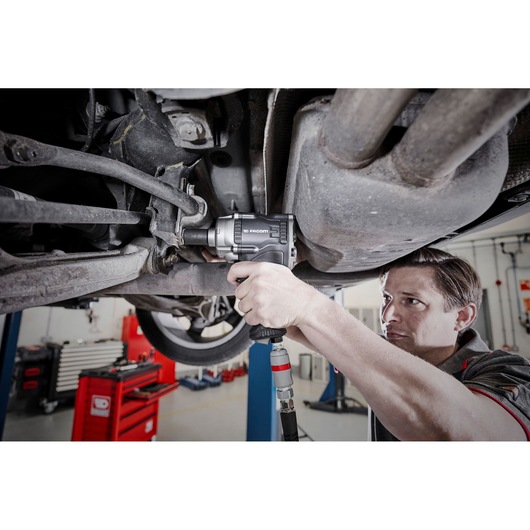 Facom NS.3100GPB impact wrench used under a vehicle in a garage, mechanic holding tool.