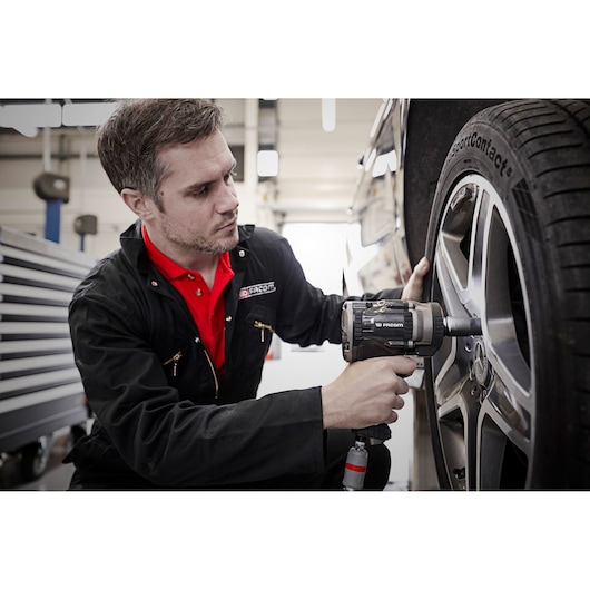 Facom NS.3500GPB impact wrench used to tighten a car wheel in a workshop setting.