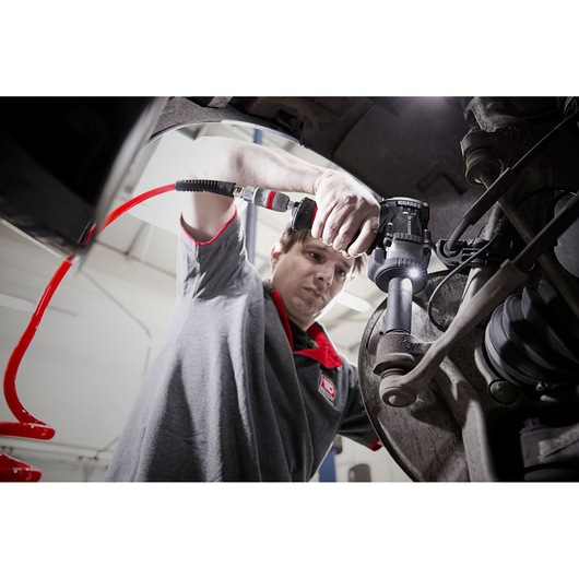 Photo of Facom NS.3500GPB mechanic using pneumatic tool on car suspension system in workshop.