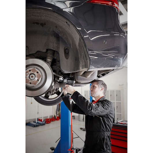 Facom NS.3500GPB automotive mechanic using impact wrench on lifted car wheel in workshop.