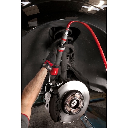 Photo of Facom NS_A1700F2 pneumatic tool in use on a car brake assembly by a gloved hand.