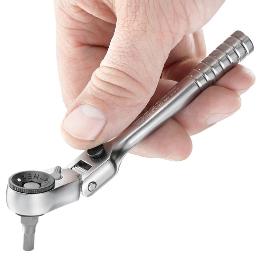 Photo of Facom R_180 compact ratchet handle in hand, silver finish, white background.