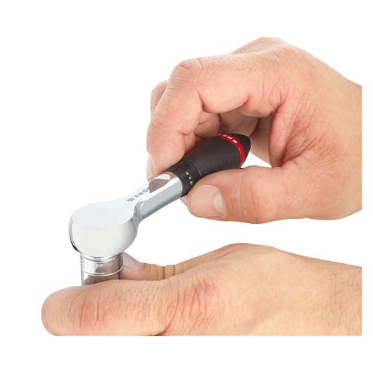 Facom R_181 ratchet with black and red handle in use, close-up on white background.