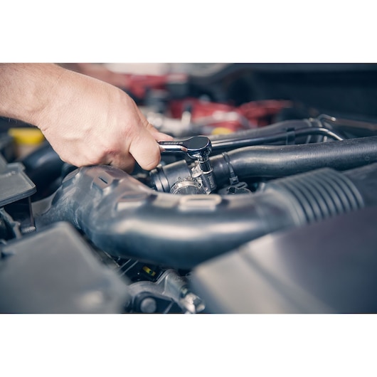 Photo of Facom R_181 ratchet being used to tighten a bolt in a car engine compartment.