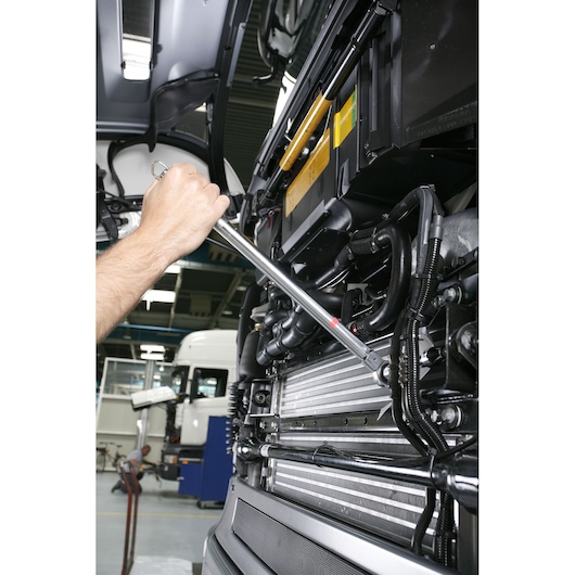 Facom R_344DA torque wrench used on truck engine in workshop setting, close-up photography.