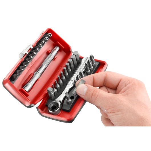 Facom R_PEJ31 photography of a red tool kit with assorted bits, ratchet and hand selecting a bit, angled view.