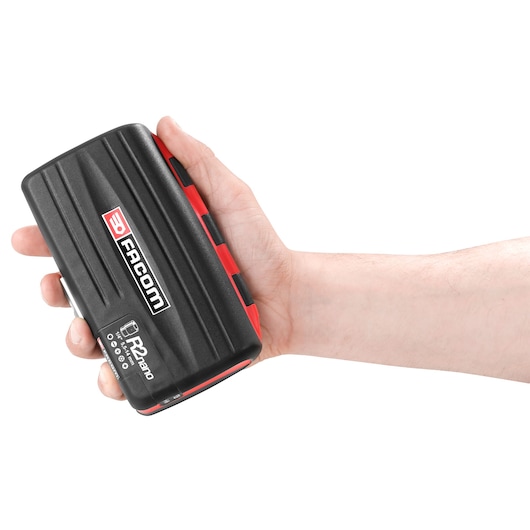 A hand holding a Facom R2nano black and red compact device, photographed against a white background.