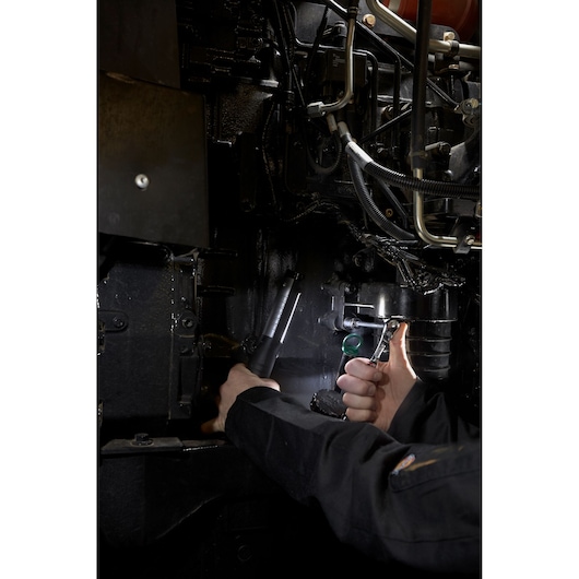 Facom RL_161 mechanic using ratchet and flashlight in dark engine bay, close-up photography.