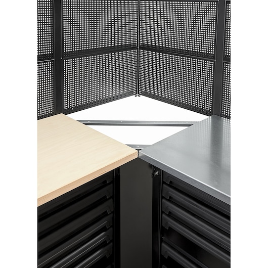 Photo of Facom RWS2-CSGBS workshop corner storage with black perforated panels, wooden and metal worktops, drawers visible.