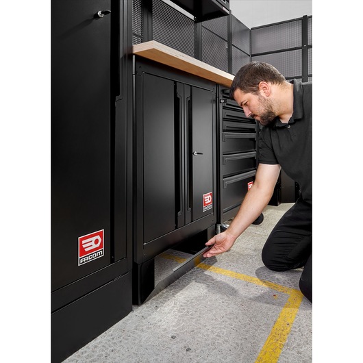 Photo of Facom RWS2-FRONTBS black metal storage cabinet with person opening bottom drawer in workshop setting.