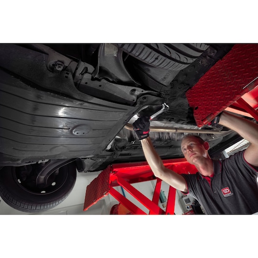 Facom S_161B ratchet wrench used by mechanic under car in workshop, side angle.