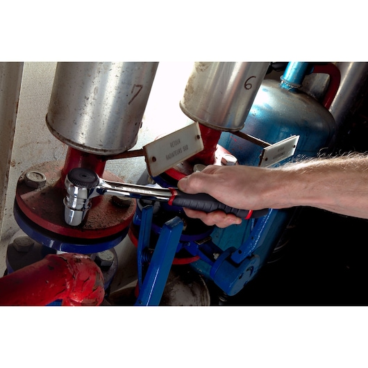 Photo of Facom S_161B ratchet wrench used by hand on industrial pipe fitting.